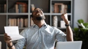 man holding piece of paper raising fist in triumph