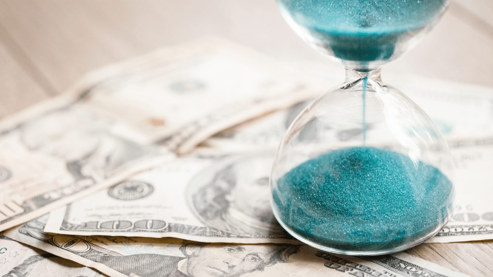 pile of money with time running out of hourglass on top
