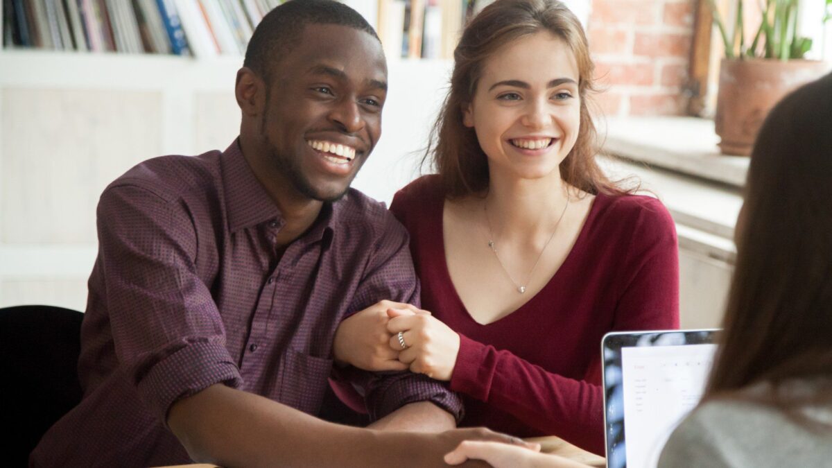 a happy couple shakes hands with a loan officer
