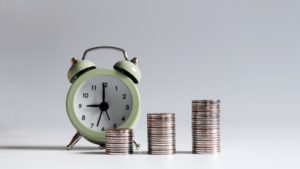 an alarm clock sits in front of stacks of coins