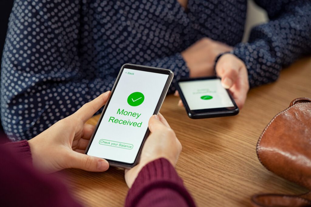 Woman looks at phone notification indicating money has been received | Auto repair financing options
