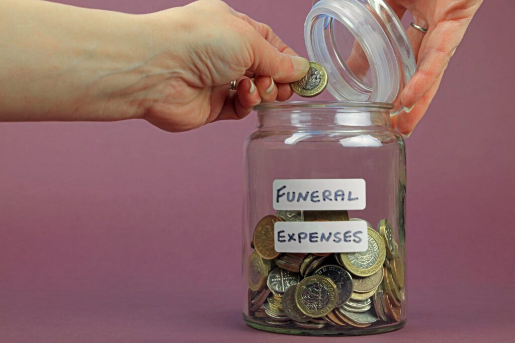 Person puts coin in jar labeled as funeral expenses | Funeral financing options