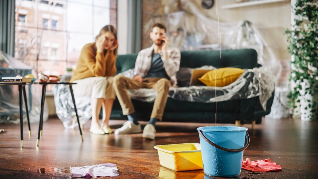 Water drips down into blue bucket as couple is calling for repairs | Home repair financing