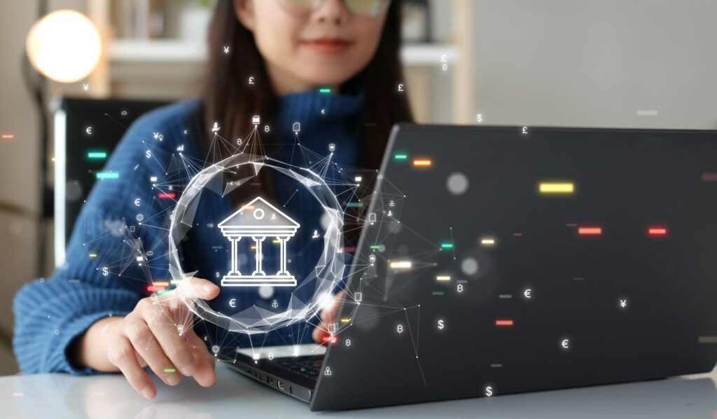 Bank logo hovers over laptop as a woman looks at online vet loan lenders | Veterinarian loan financing
