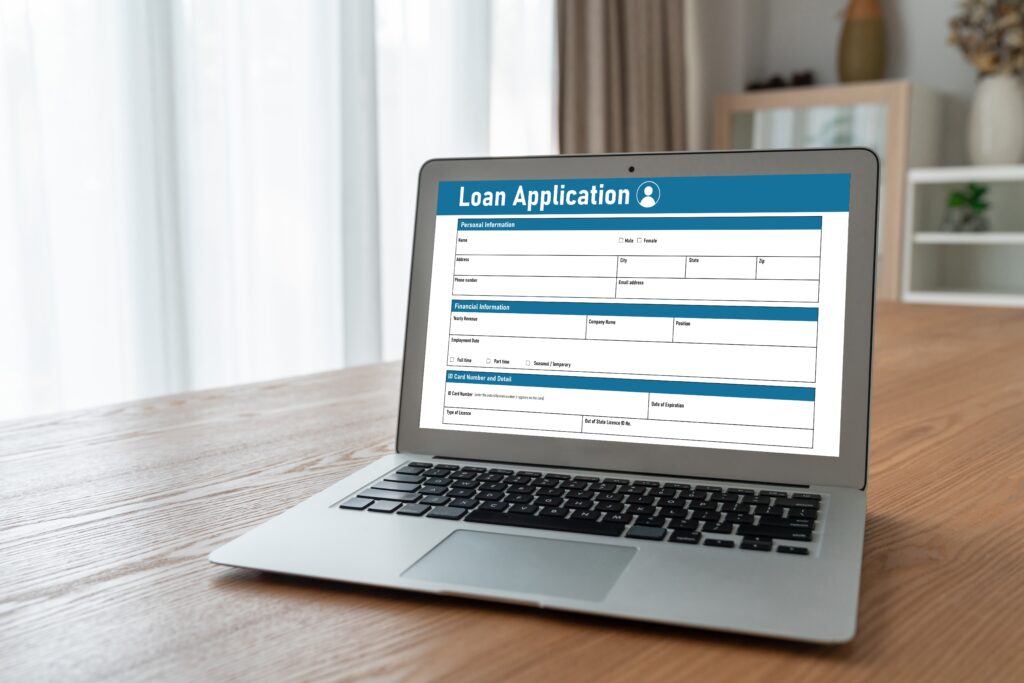 Blue loan form displays on a gray laptop sitting on a desk | Veterinarian loan financing