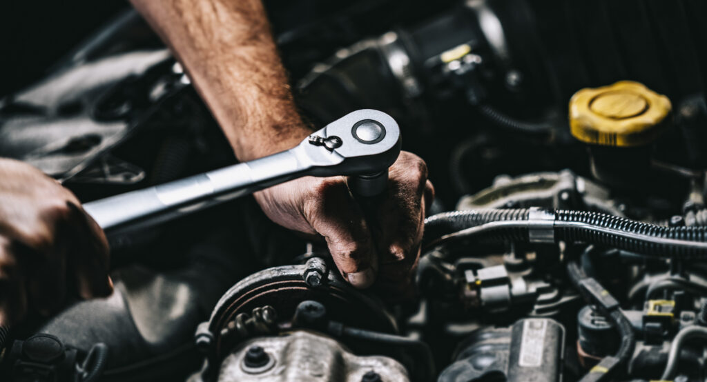 Close up of mechanic using wrench to tighten bolt in engine | How to get an auto repair loan