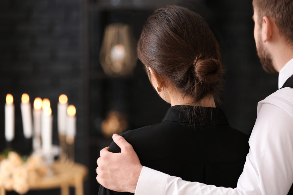 Close up of man holding woman's shoulder to comfort her during funeral | How to get a funeral loan