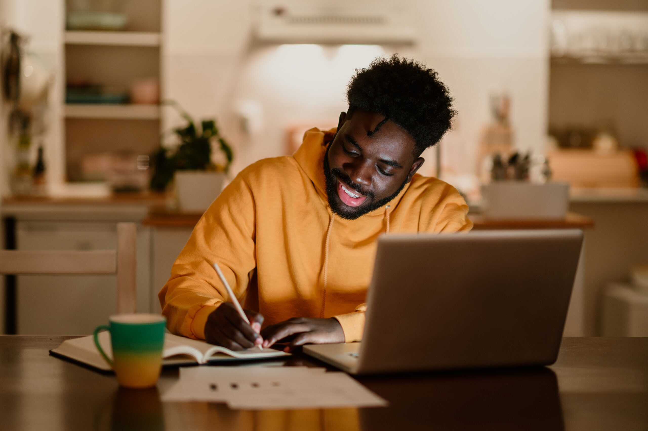 Man in yellow hoodie smiles as he takes notes on installment loans | Best installment loans