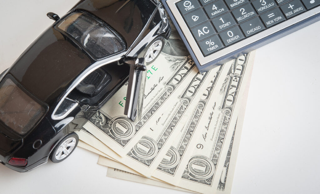 Aerial view of model car and calculator resting on top of dollar bills | How to get an auto repair loan