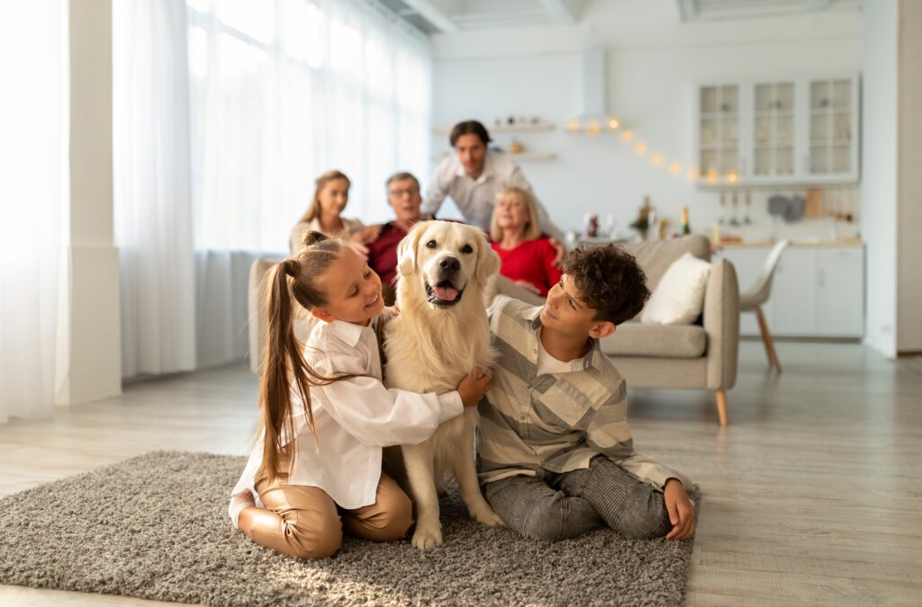Smiling grandparents and parents sit on a couch as two kids play with golden retriever | Ways to pay emergency vet bills