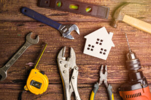 Paper cutout of a house sits on table full of various power tools | How to get a home repair loan