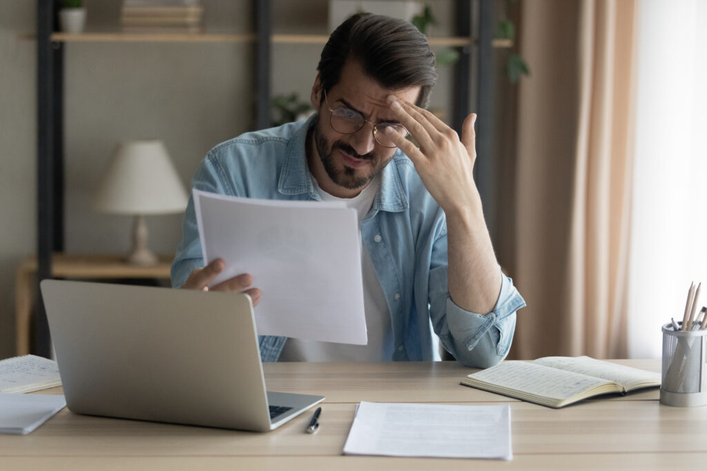 Concerned man touches forehead as he reviews unexpected bill | Planning for unexpected expenses