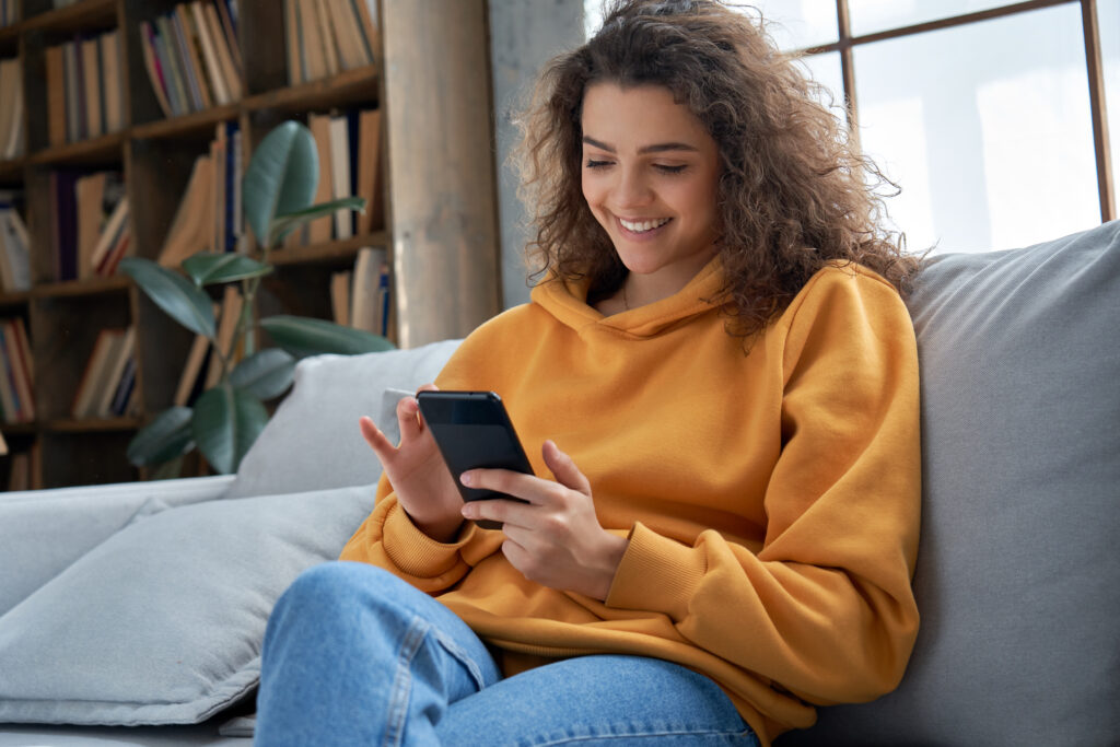 Woman smiles while sitting on couch and exploring Wise Loan solutions | Ways to get emergency money