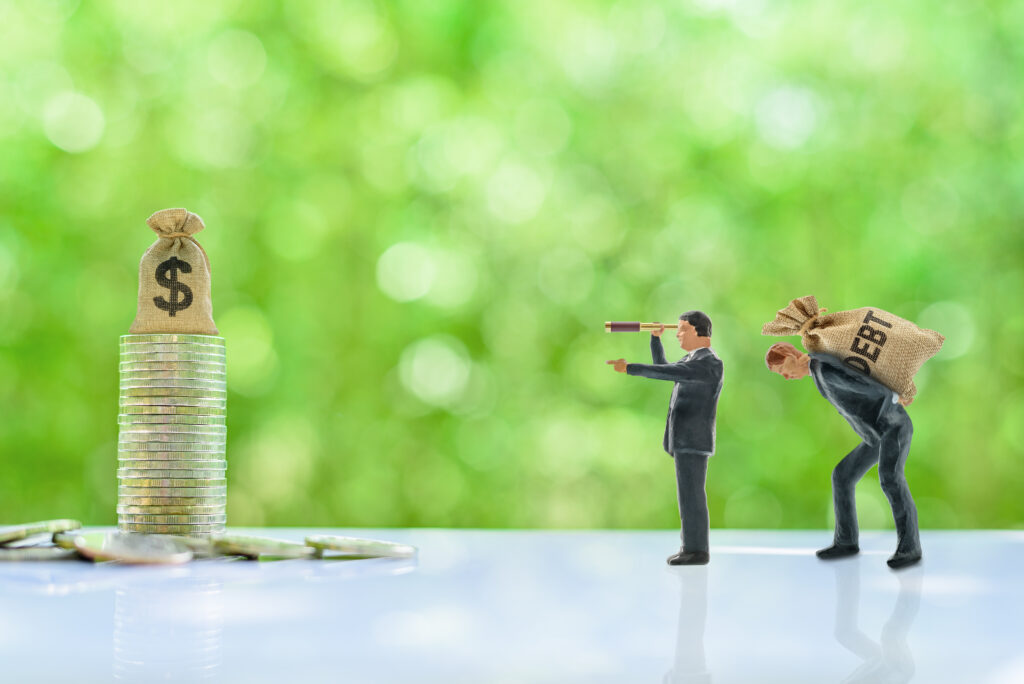 Small male figurines holding bag of debt use telescope to look at coin stack across wooden desk | Best installment loans for bad credit