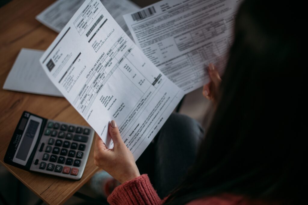 Sitting woman looks at unexpected bills next to calculator on desk | Planning for unexpected expenses