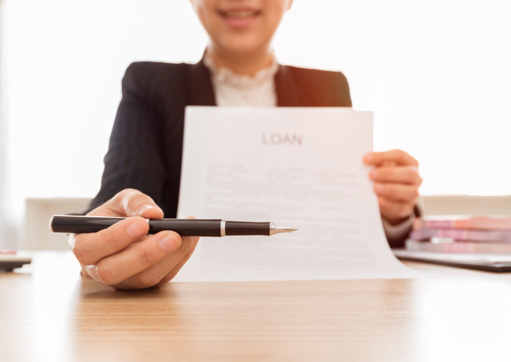 Close up of woman holding loan agreement as she offers black ballpoint pen | Best emergency loans